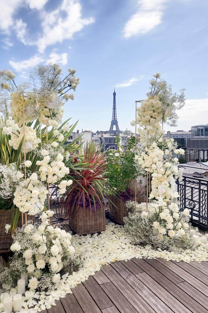 Romantic rooftop elopement setup at Hotel Marignan in Paris with two grand fresh flower columns facing the Eiffel Tower, ideal for intimate weddings or proposals
