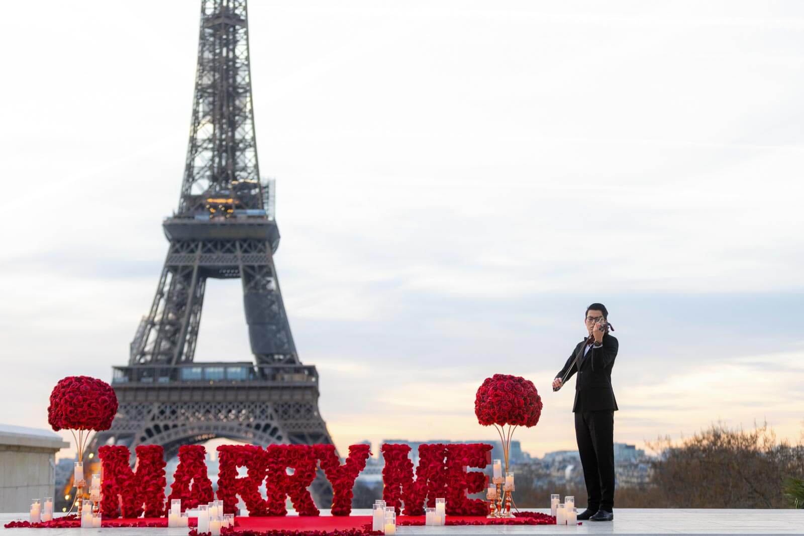 Red 'Marry Me' setup at sunrise on Trocadéro with a master musician and Eiffel Tower view – ideal for a romantic marriage proposal in Paris.