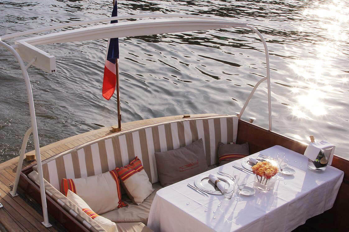 Romantic private dinner cruise Paris setup on a Paris yacht with soft sunlight reflecting on the Seine.